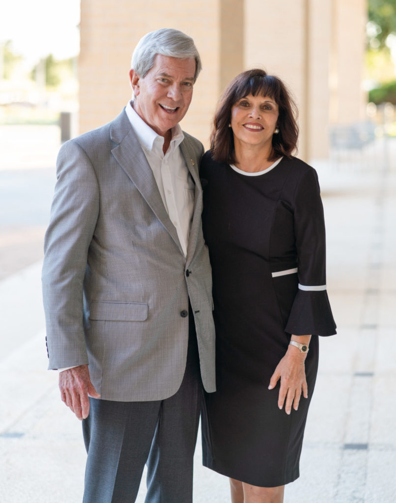 A man and woman - Bill and Fran Carter - stand in front of a a building. 