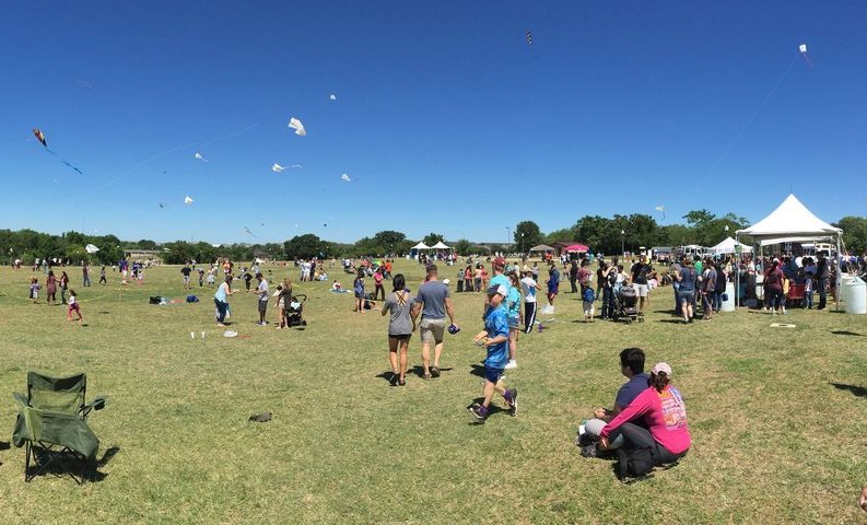 People out on a lawn with chairs and tents at Kite Fest