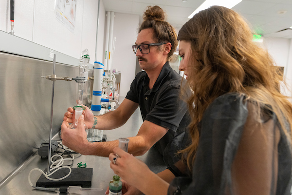 Two students working with lab equipment used for enology.