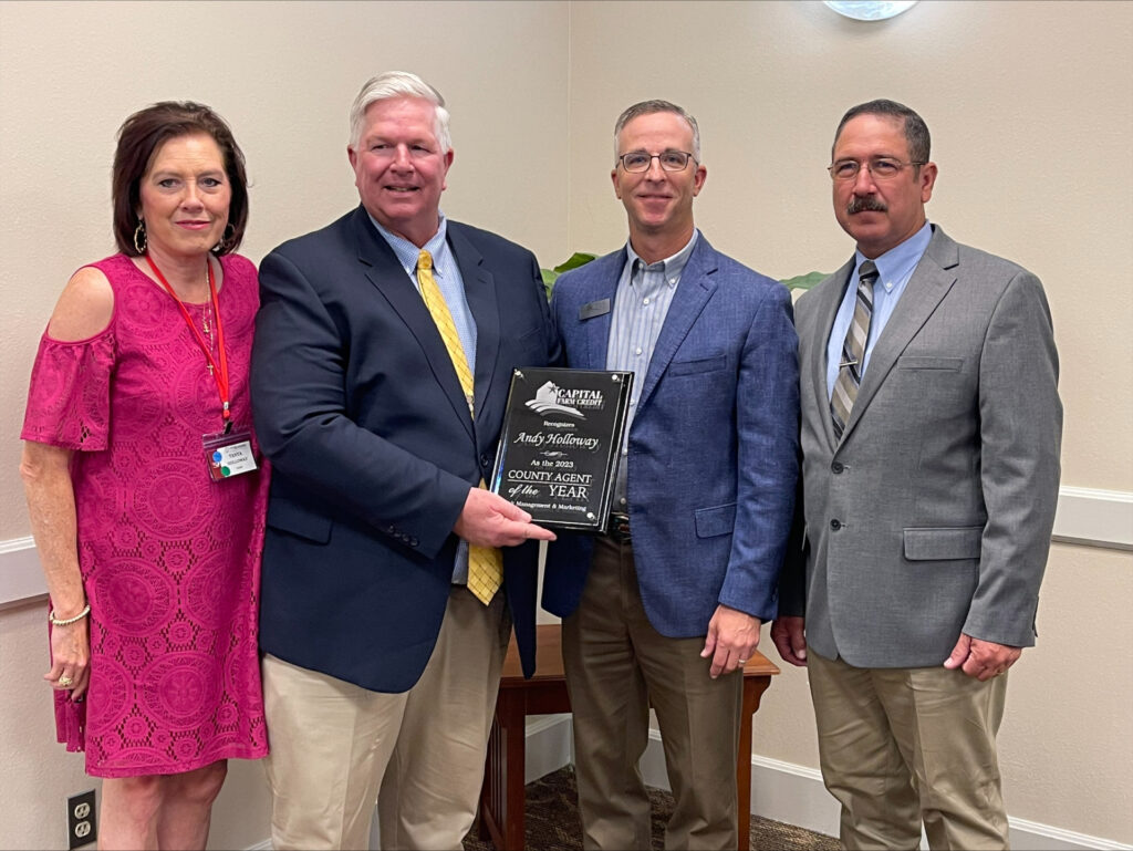 Four people posing for a picture after Andy Holloway received his award.