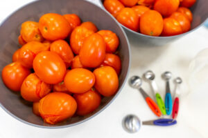 Two bowls of tomatoes on a table.
