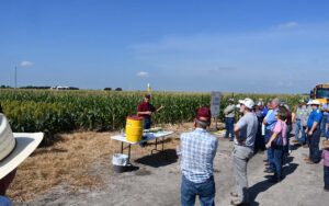 A man is demonstrating a field trial to a group of people at the Stiles Farm in Thrall.