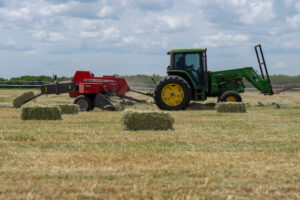Heavy machinery converting loose hay into small bales