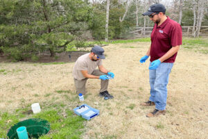 Two men in a field checking a septic system