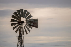 The top portion of a windmill against a cloudy sky