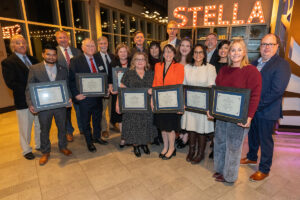 group shot of award winners with many of them holding framed certificates