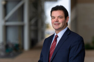 Portrait of a man, Lorenzo Rossi, Ph.D. he is wearing a light blue shirt with a red stripped tie and a blue suit jacket.