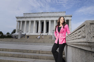 Brooke Rollins in a pink jacket stands outdoors