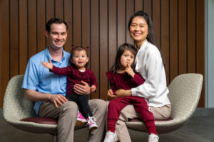 A father and a mother sit with their two daughters on their laps.