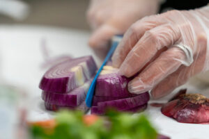 Closeup of hands with knife cutting a purple onion
