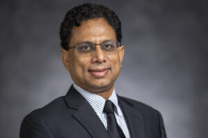 Binayak Mohanty - a man in glasses and a dark suit