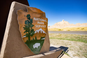 A national park entry sign with a mountain in the background.