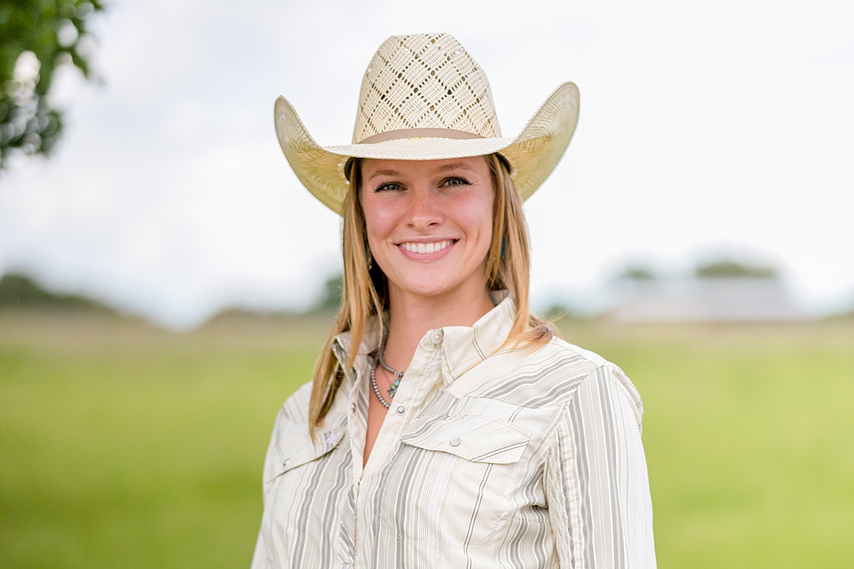 A woman in a cowboy hat in a green field.
