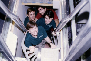 Four people stand in a stairwell looking up.