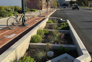 A street with a bike on the sidewalk and multiple planters